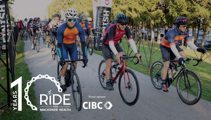 A group of cyclists pedaling down a pathway at the beginning of their ride. Image overlay with the Ride for Mackenzie Health logo presented by CIBC